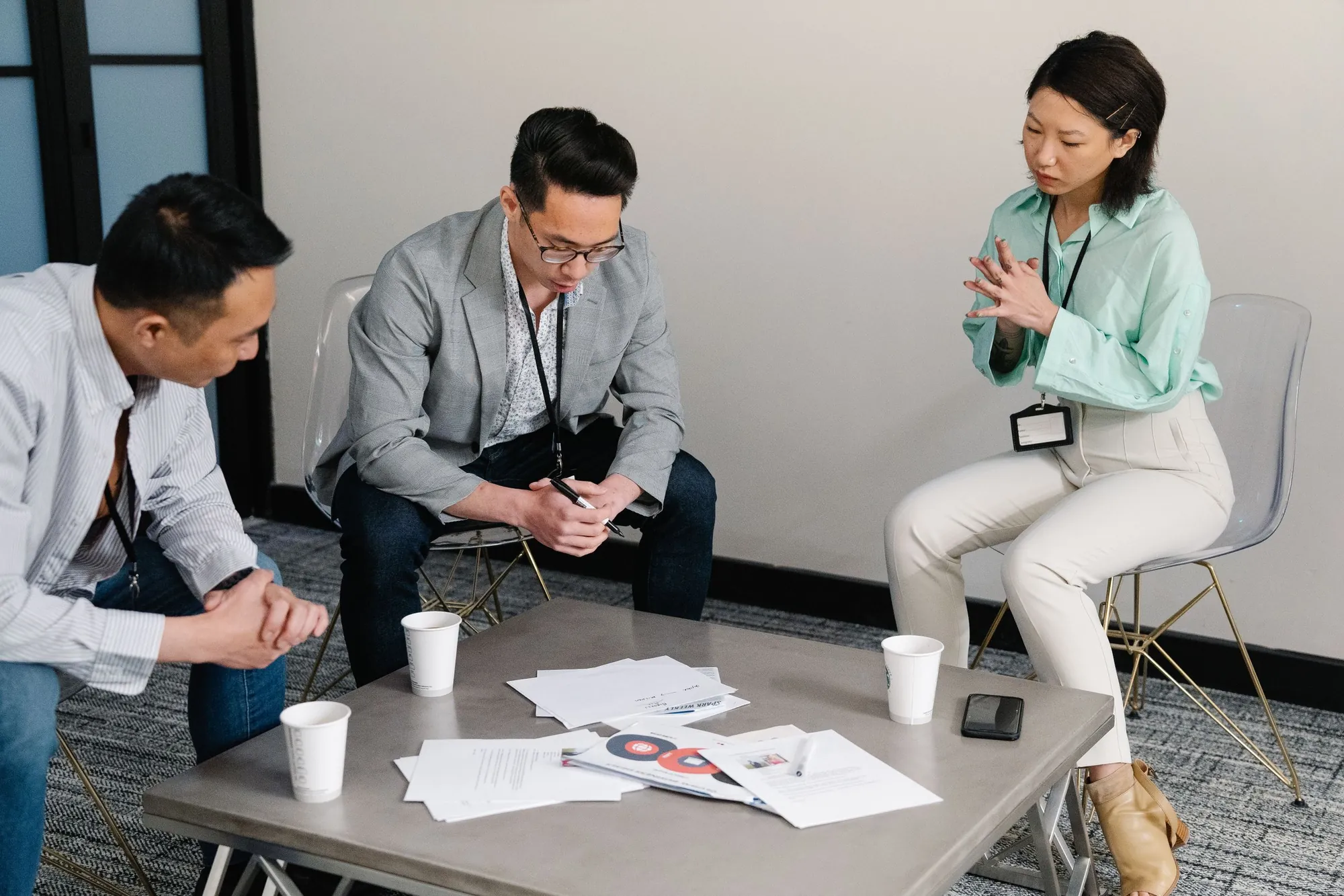 Three colleagues discussing papers around a table