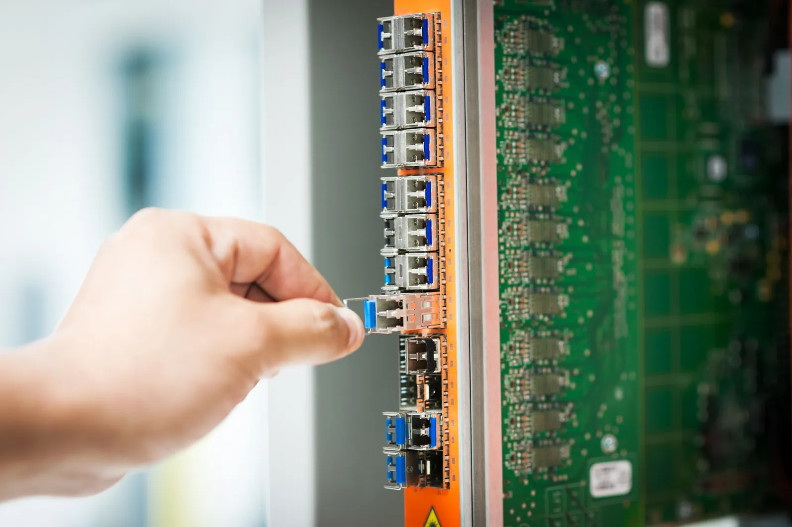 A hand plugging a connector into a port on a network panel