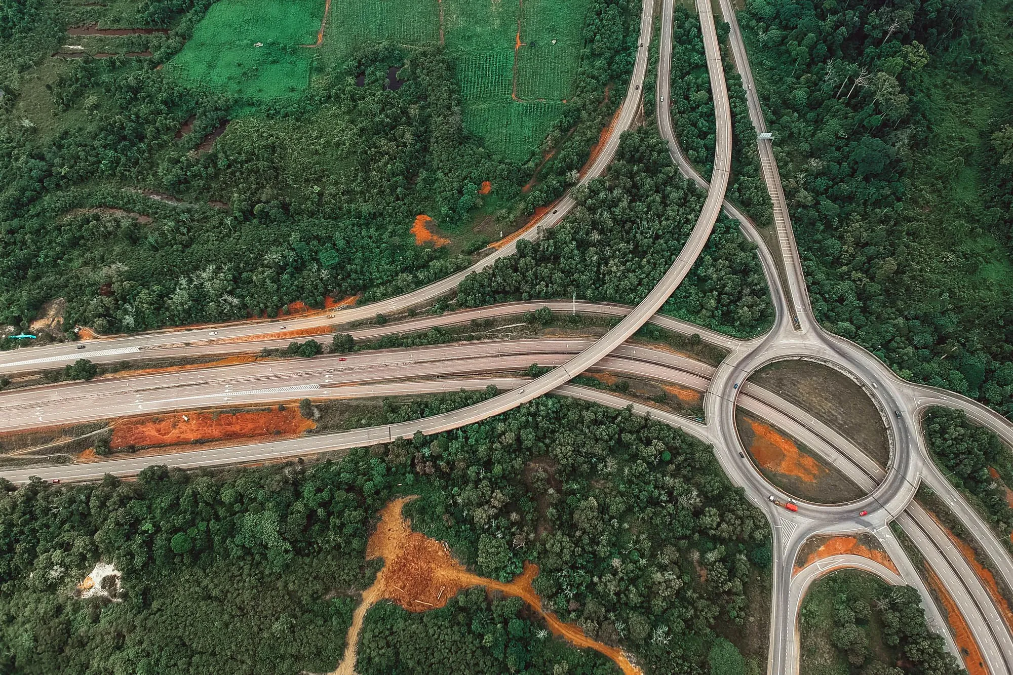 Roads branching out from a roundabout through green country, seen from above