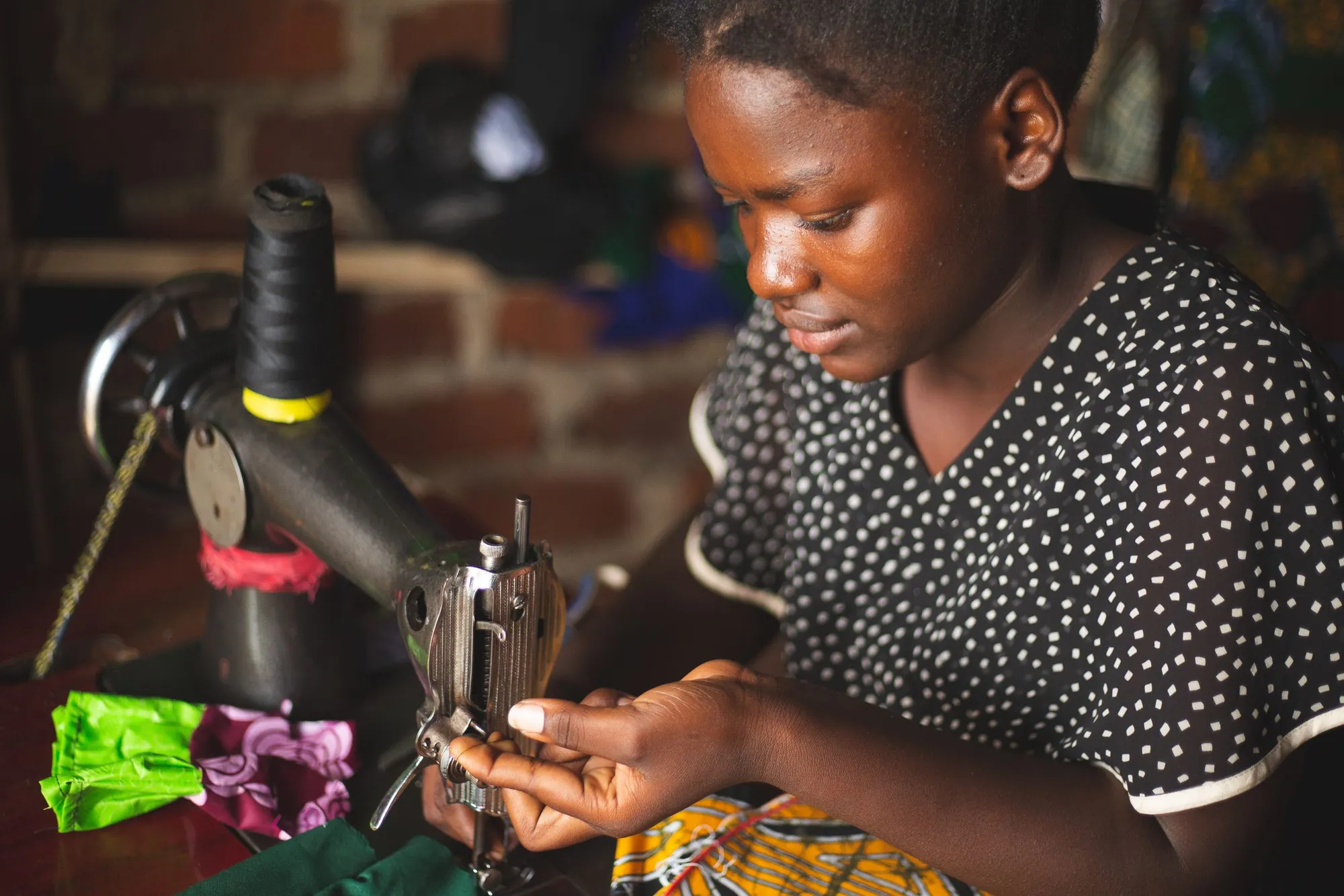 A seamstress threading her sewing machine in a small workshop